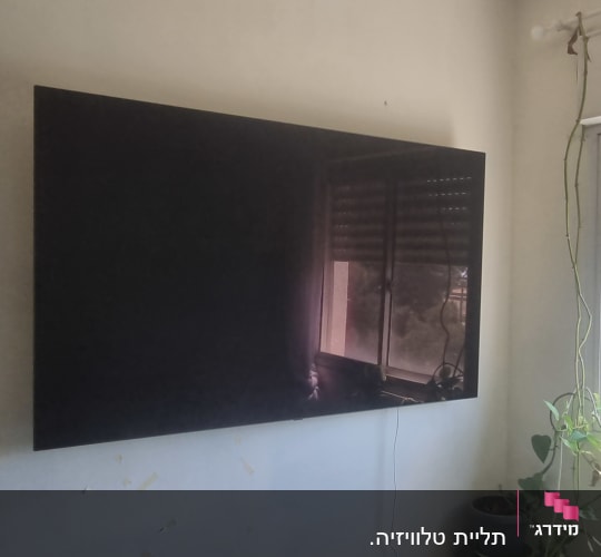 טלוויזיה תלויה על הקיר עם כבל חשמל